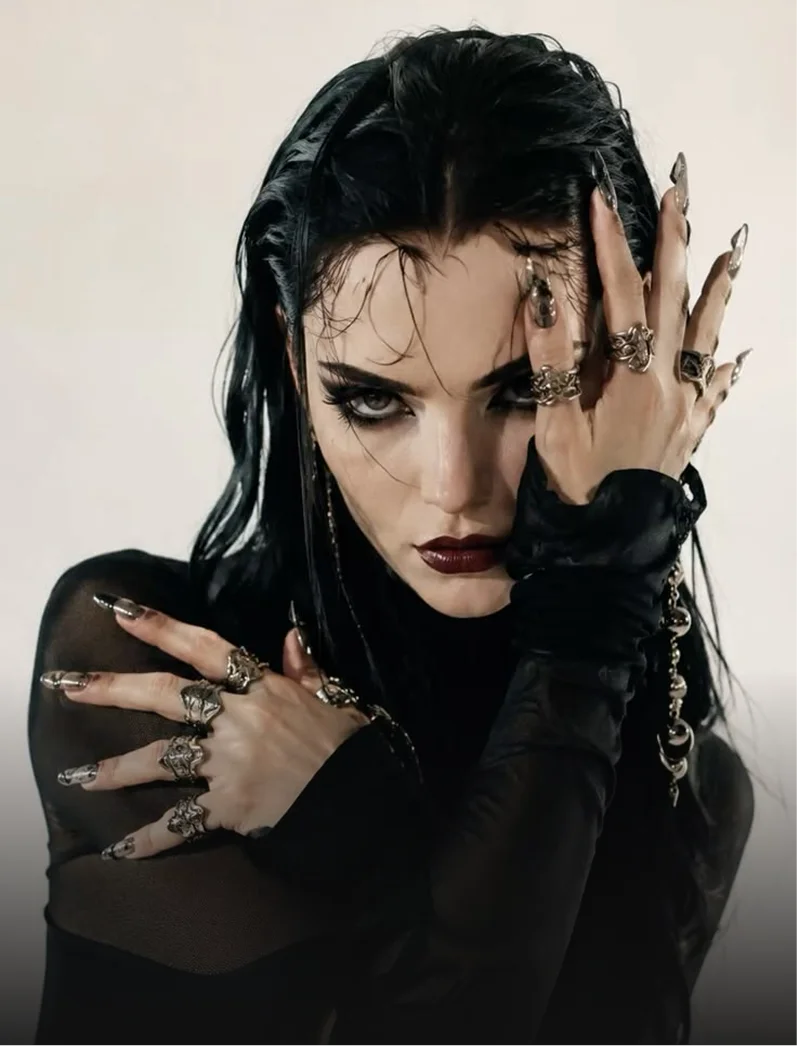 Mujer de cabello negro largo y anillos plateados con la mano sobre la cara